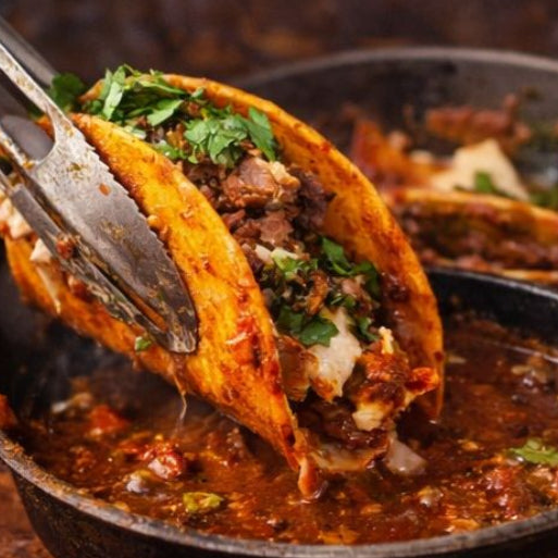 Tacos being lifted from a pan with text 'Growth means evolution' and 'Birria Gold Seasoning' at the bottom.